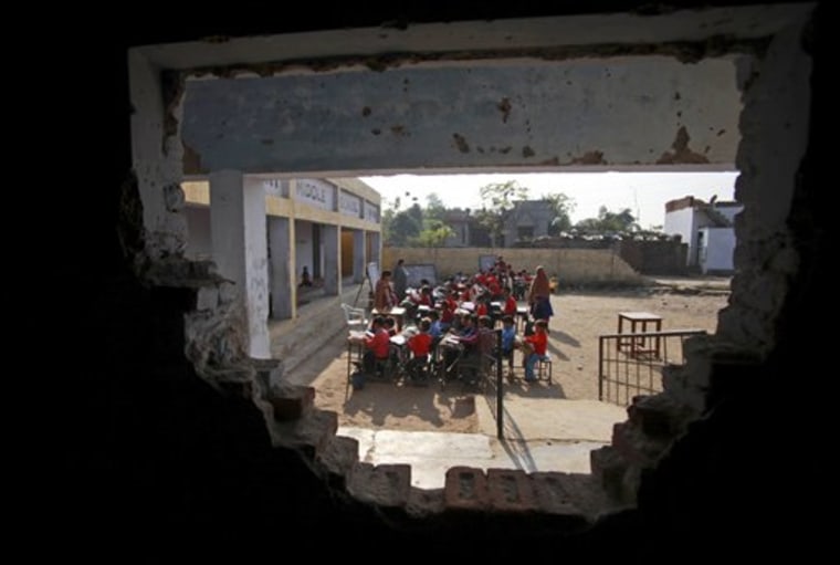 Indian schoolchildren are seen through a damaged wall at a government school in the outskirts of Jammu, India, Thursday. Indian technology mogul Azim Premji has announced he will donate nearly $2 billion to fund education and development programs in India's villages.